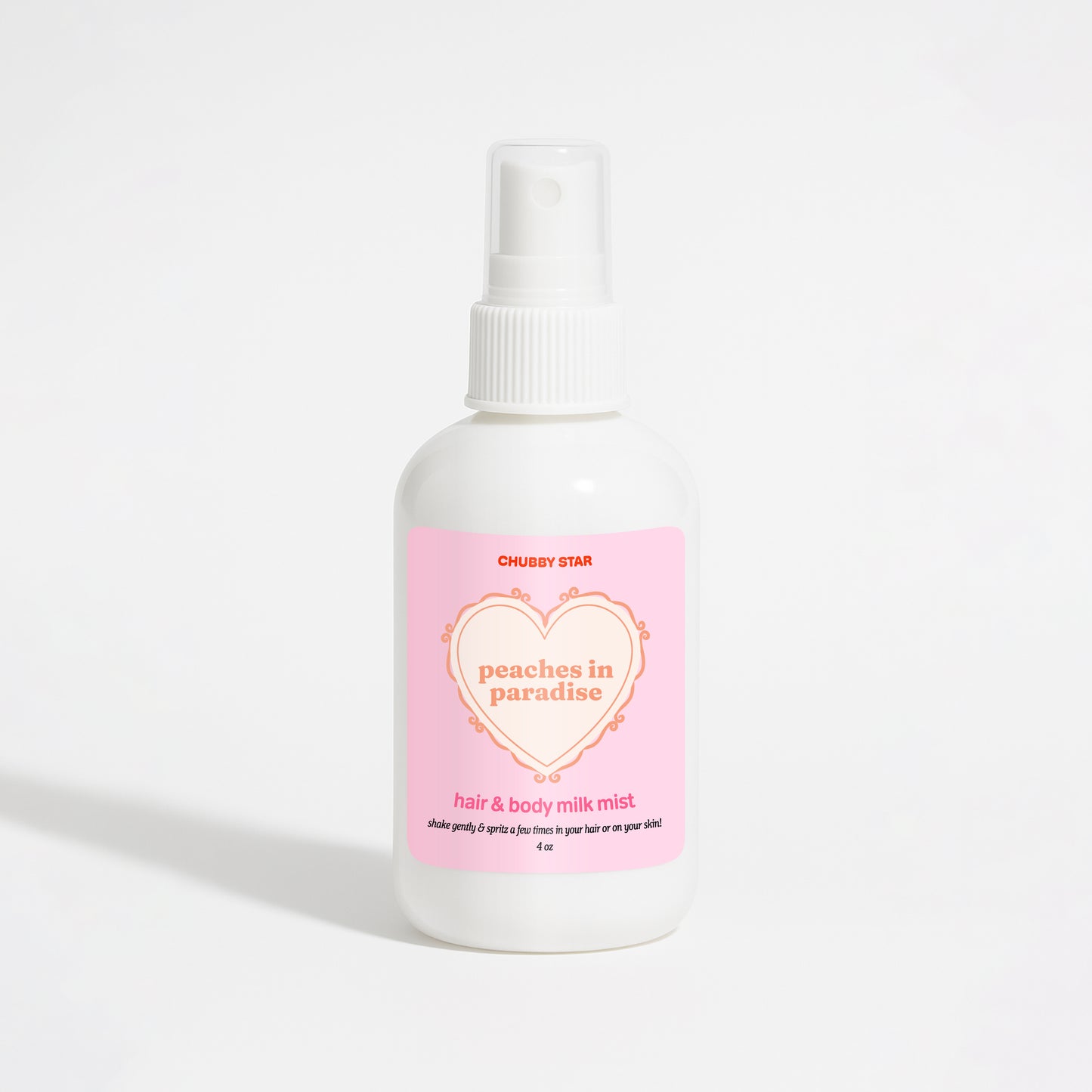 A white plastic spray bottle of Chubby Star Peaches in Paradise Kayali Eden Sweet Peach 35 scented hair & body milk spray with a pink label, set against a plain white background.