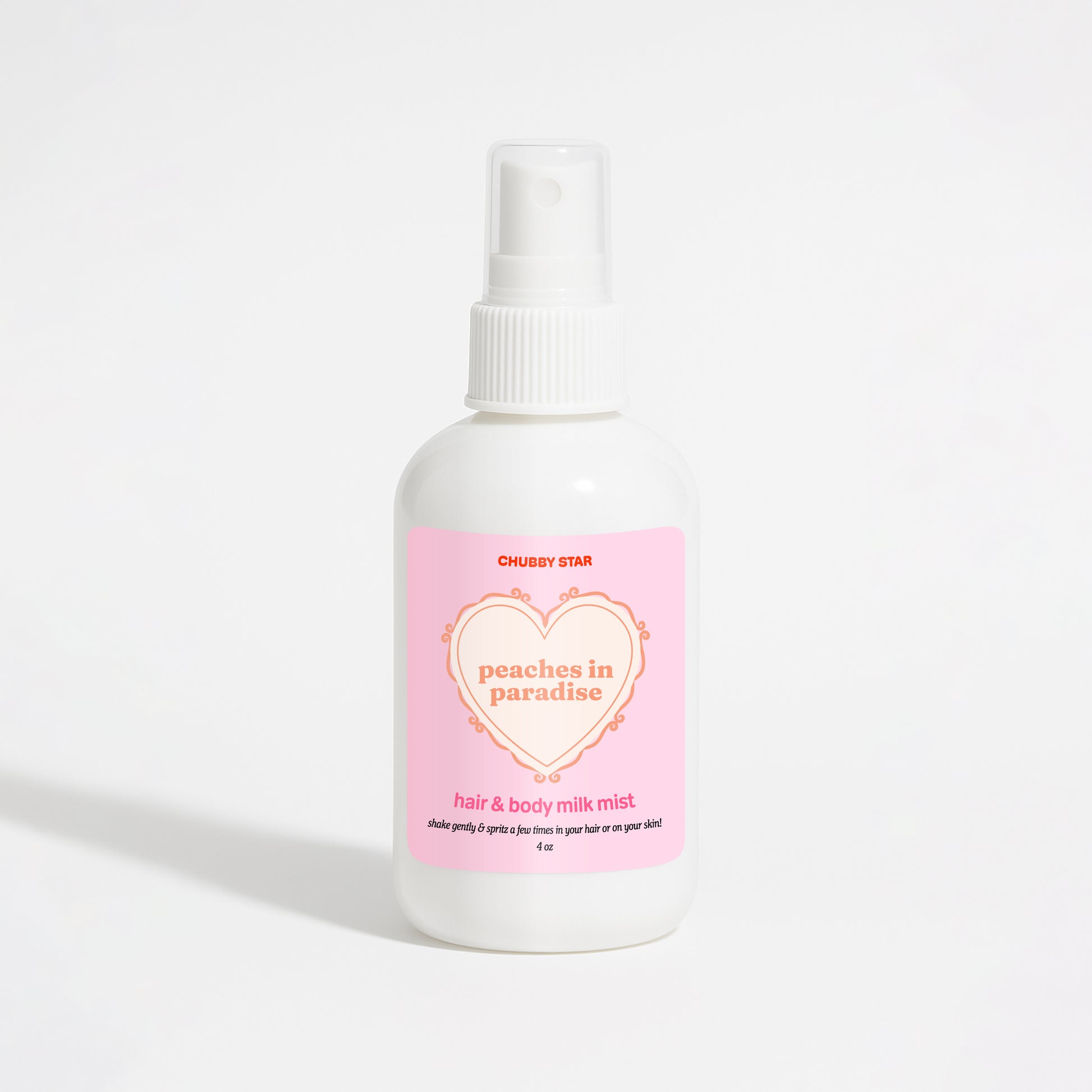 A white plastic spray bottle of Chubby Star Peaches in Paradise Kayali Eden Sweet Peach 35 scented hair & body milk spray with a pink label, set against a plain white background.
