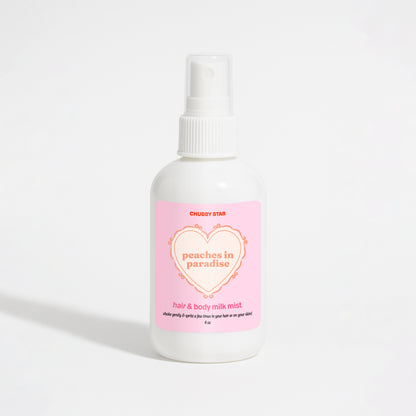 A white plastic spray bottle of Chubby Star Peaches in Paradise Kayali Eden Sweet Peach 35 scented hair & body milk spray with a pink label, set against a plain white background.