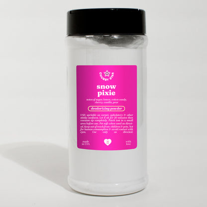 A clear plastic jar of Snow Pixie, a Lush Snow Fairy Dupe, Scented Deodorizing Powder with a black lid and a bright pink label, set against a plain white background.