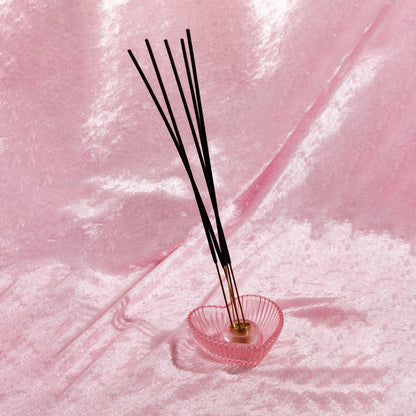 Heart-shaped incense holder with incense sticks on a pink velvet background. Incense sticks smell like designer dupe fragrances, made by Chubby Star in the USA